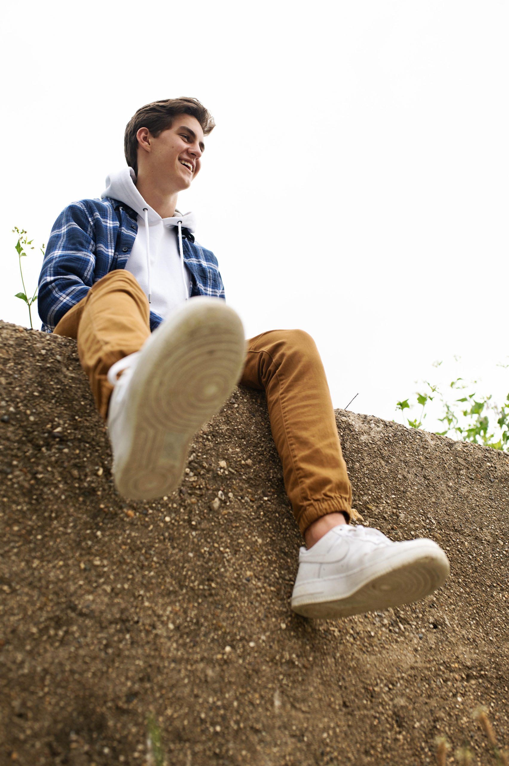 HIgh school senior boy sitting on a cement wall wearing airforce ones in the Quad Cities